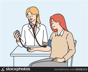 Woman undergoes medical examination at doctor using stethoscope and device for measuring blood pressure. Girl patient sitting at table near doctor undergoing physical examination. Woman undergoes medical examination at doctor using device for measuring pressure