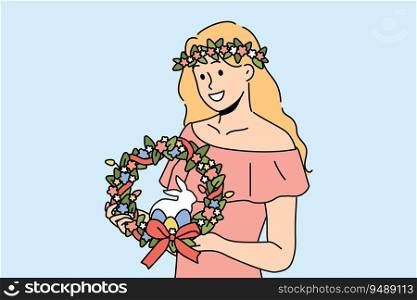 Woman with easter wreath on head smiles and holds colored eggs and miniature rabbit. Girl dressed in pink dress with easter accessories inviting to celebrate religious christian holiday. Woman with easter wreath on head smiles and holds colored eggs and miniature rabbit