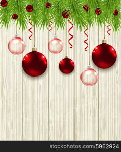 Wooden Christmas background with green fir branches and red baubles