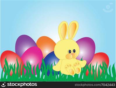 Yellow Easter bunny sitting in the grass near colourful eggs