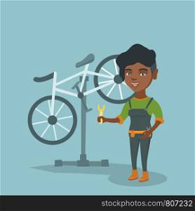 Young african-american bicycle mechanic showing a spanner on the background of broken bicycle. Technician repairing bicycle in repair shop. Vector cartoon illustration. Square layout.. African bicycle mechanic working in repair shop.