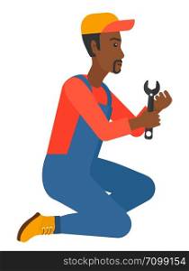 Young african-american repairman sitting with a spanner in hand vector flat design illustration isolated on white background. . Repairman holding spanner.
