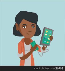 Young african-american woman recharging her smartphone with a mobile phone portable battery. Smiling woman holding a mobile phone and a battery power bank. Vector cartoon illustration. Square layout.. Woman reharging smartphone from portable battery.