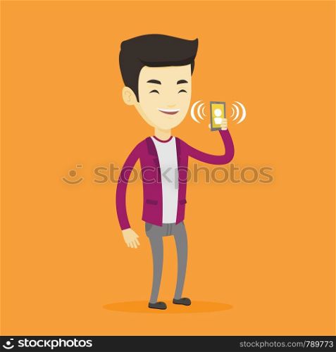 Young asian man holding ringing mobile phone. Smiling man answering a phone call. Man standing with ringing phone in hand. Vector flat design illustration isolated on blue background. Square layout.. Man holding ringing mobile phone.