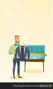 Young caucasian white man packing his clothes in an opened suitcase. Smiling man putting a jacket into a suitcase. Cheerful man preparing for vacation. Vector cartoon illustration. Vertical layout.. Caucasian man packing clothes in a suitcase.
