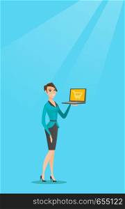 Young caucasian woman using a laptop for shopping online. Happy woman holding a laptop with a shopping trolley on screen. Woman doing online shopping. Vector flat design illustration. Vertical layout.. Woman holding laptop with trolley on a screen.