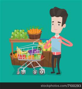 Young man standing near trolley full with products. Customer holding shopping list on the background of supermarket section with vegetables and fruits. Vector flat design illustration. Square layout.. Man with shopping list vector illustration.